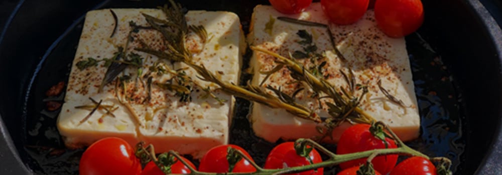 Feta mit Kräutern und Tomaten in der Pfanne auf dem Grill