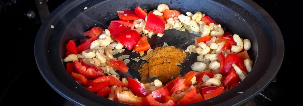 Zwiebeln, Knoblauch, Fenchel, Paprika und Cashewkerne mit Gewürzen in Tajine