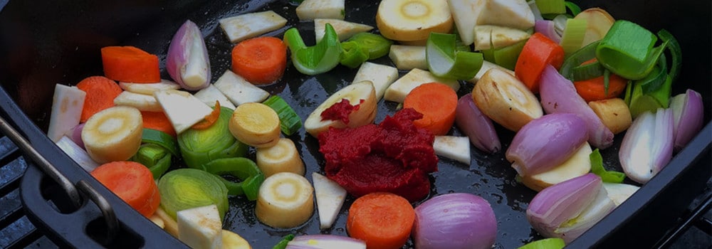 Schalotten- und Gemüsestücke mit Tomatenmark zum Andünsten im Dutch Oven