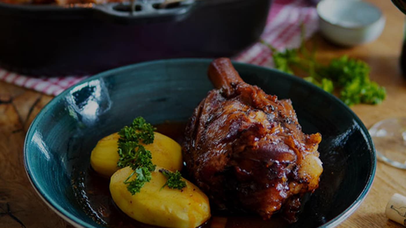 Geschmorte Schweinehaxe aus dem Dutch Oven vom Grill angerichtet mit Kartoffeln