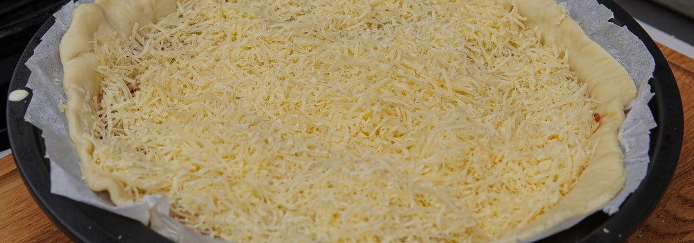 Zwiebelkuchen in der Form mit Käse bestreut