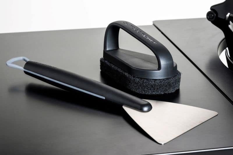 Outdoorchef Reinigungset bestehend aus Power-Reiniger, Grillbürste und Reinigungstüchern auf der Seitenablage eines Grills.