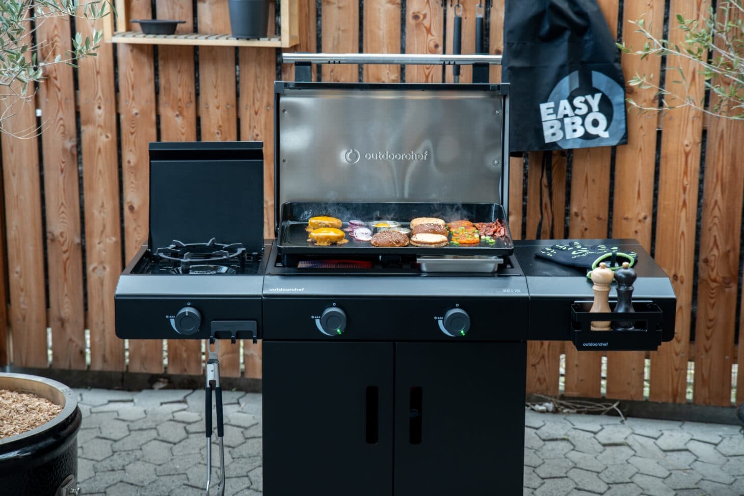Outdoorchef Planchagrill Heat C-265 frontal auf der Terrasse mit Plancha, Burgern und Grillzubehör