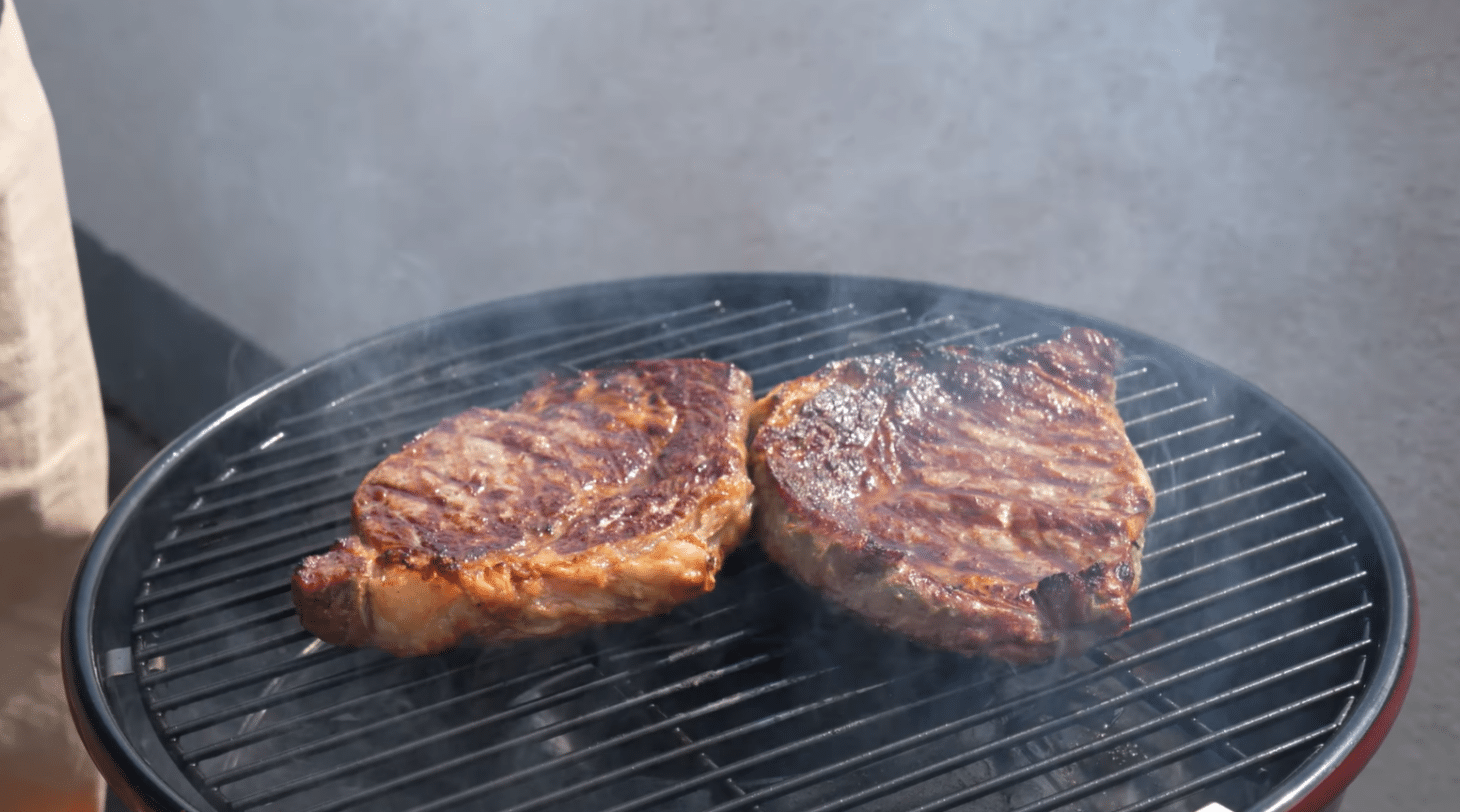 Outdoorchef City 420 G mit zwei Steaks auf dem Grillrost beim Grillen